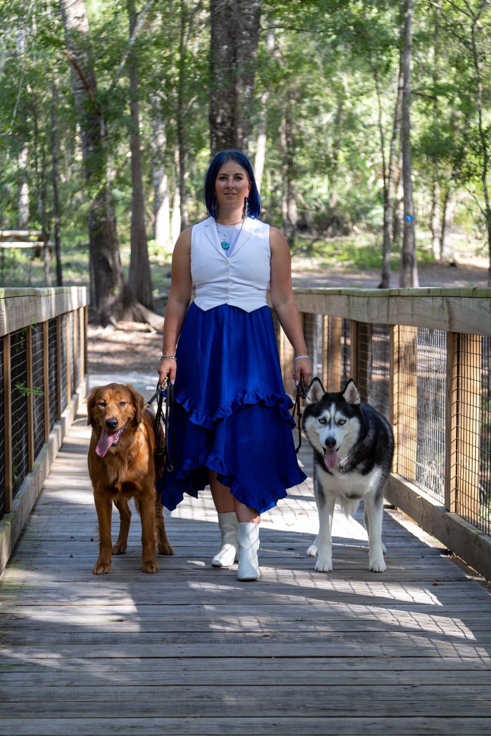 Cindi Quick walking Tonka and Stella on a wooded boardwalk